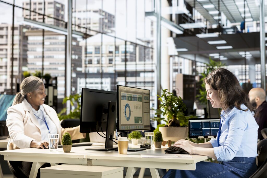 Due professioniste analizzano dati di bilancio e business intelligence in ufficio moderno.